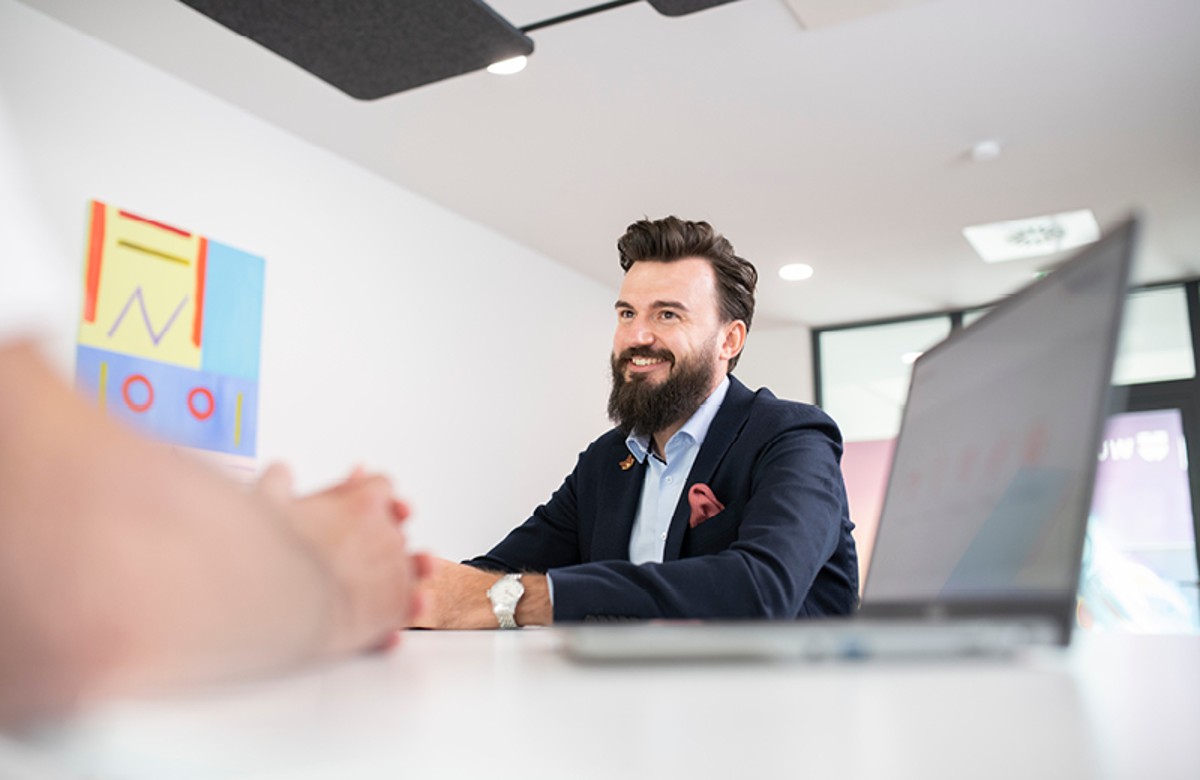 Porträt von Mitarbeitendem mit Laptop